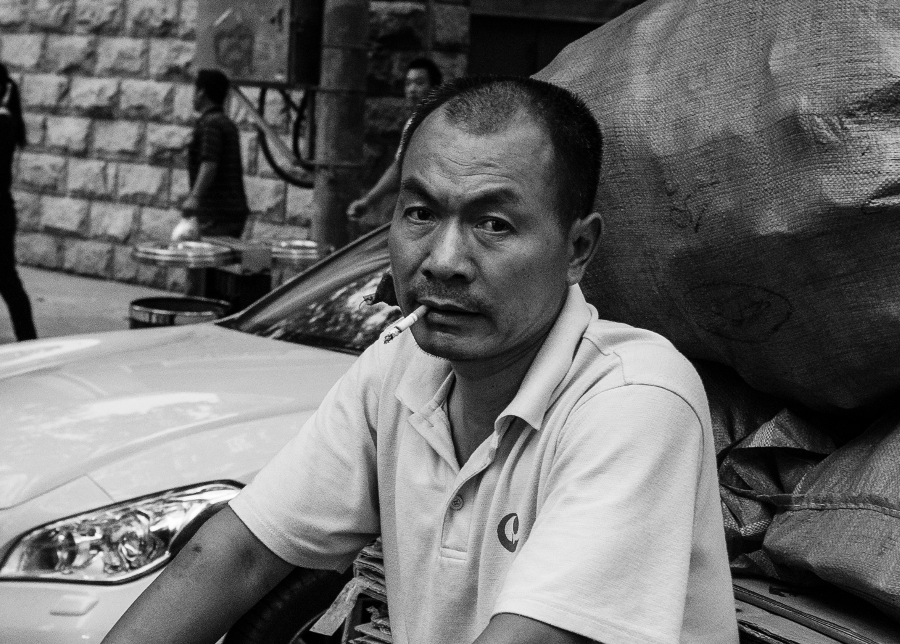 Peking; man smoking a cigarette while driving a bike