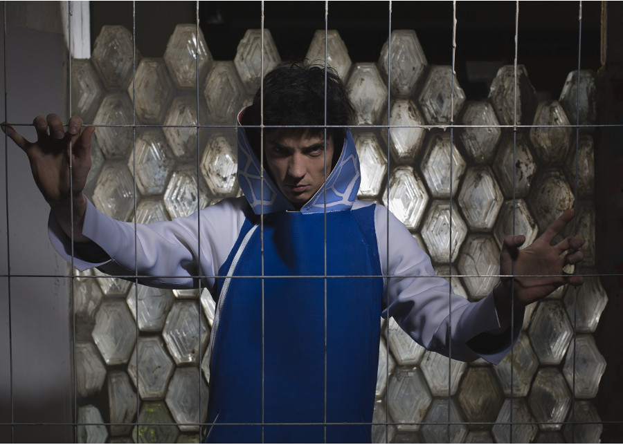 a man behind a fence, wearing a blue jacket