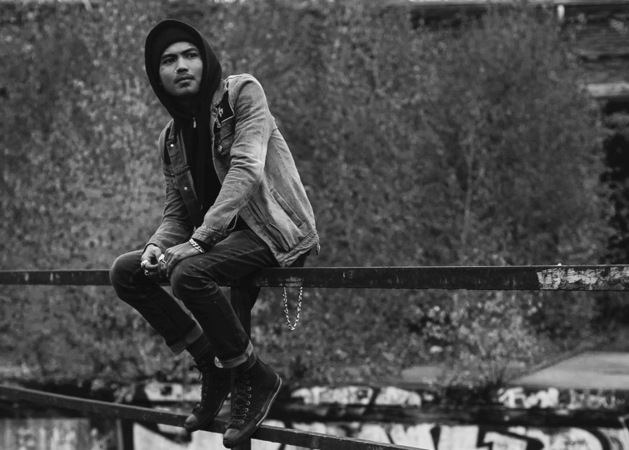 a guy is wearing a hoodie while sitting on a bar