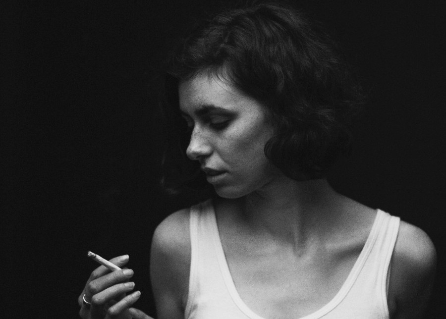 girl smoking a cigarette, while her arm is behind her back