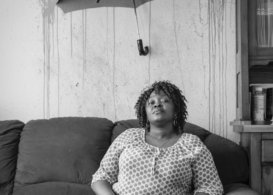 a woman is sitting on a couch under an umbrella